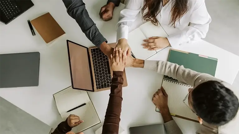 Team of people stacking their hands in a circle